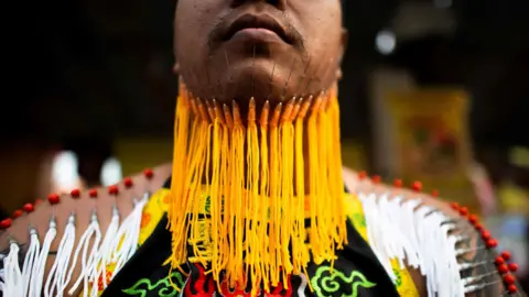 AFP A devotee of the Loem Hu Thai Su shrine waits to parade with needles pierced through his chin