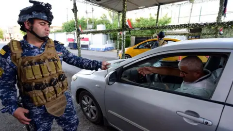 EPA Iraqi police officer checks the identity papers of a driver in Baghdad's Karrada district (12 May 2019)