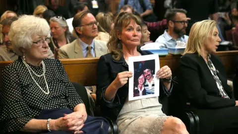 Getty Images An attendee holds a photo of Cheri Domingo and her boyfriend Gregory Sanchez, who were killed in 1981.