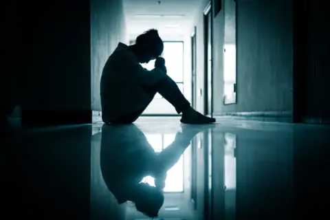 Getty Images Sad teenager sits in a corridor