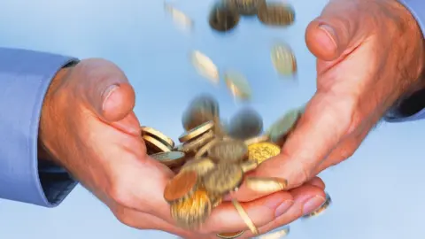 Getty Images Coins falling through hands