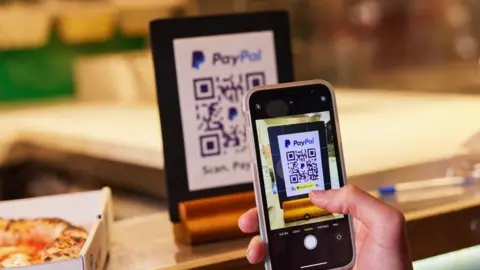 PayPal Person scans QR code with PayPal app.