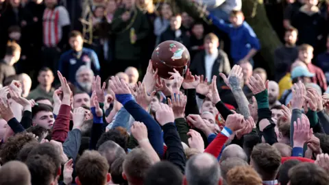 Reuters An image of dozens of people fighting for a football during Royal Shrovetide Football