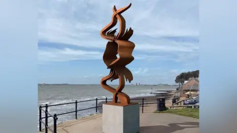 The CGI design for the installation, on a plinth, with the sea in front of it