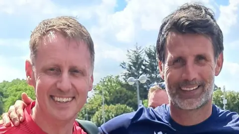 Glen Worrell Glen Worrell, wearing a red top, poses arm in arm for a photograph with Danny Cowley, who is wearing a navy top. They are both smiling on a sunny day.