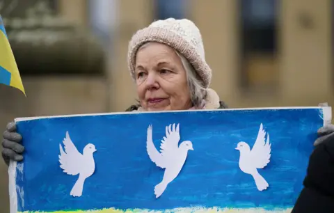 Ian Forsyth/Getty Images A woman holds a banner as members of northeast Ukrainian community groups gather at Grey's Monument to mark the first anniversary of the Russian invasion of Ukraine, on February 24, 2023 in Newcastle upon Tyne, United Kingdom.