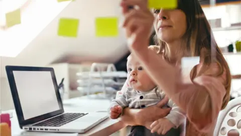 Getty Images Mother working with child on lap