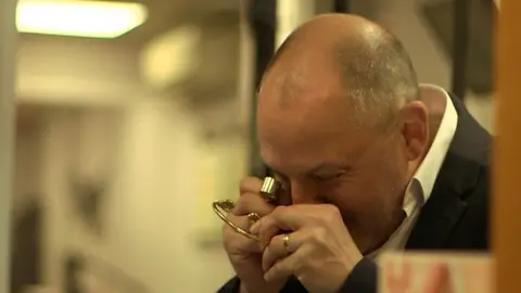 A pawnbroker inspects a gold bracelet