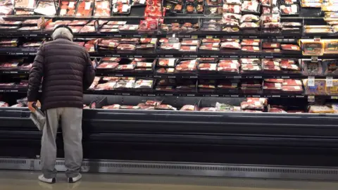 Getty Images a man looks at meat in a grocery store