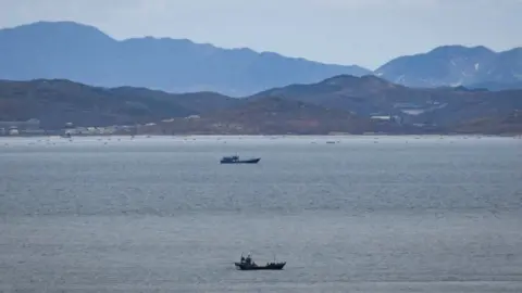 Getty Images Unidentified fishing boats before the North Korean coastline from a viewpoint on the South Korea-controlled island of Yeonpyeong near the disputed waters of the Yellow Sea at dawn.