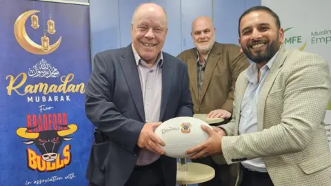 BBC/Aisha Iqbal Rugby fan Graham Swain with Humayun Islam of the Muslim Friendly Employers project and (background) Nigel Wood, chairman of Bradford Bulls