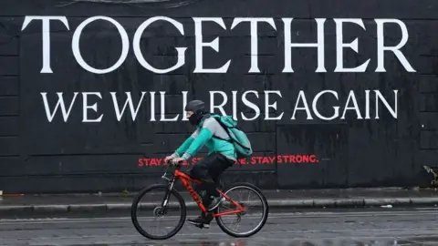 PA Media A cyclist passes a mural in Dublin City centre as the Irish government considers new coronavirus restrictions