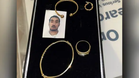 Essex Police Gold bracelets, earrings and a ring laid out on a black surface. There is also a passport photo of Deveire Young