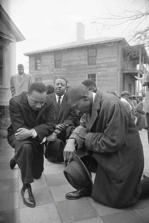 Getty Images Martin Luther King Jr kneeling outside a courthouse in Alabama