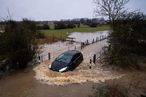 PA Media Cars pass through a flooded road in Leicester, on 14 January 2021