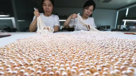 Getty Images Workers sort out pearls at a factory on July 20, 2022 in Huzhou, Zhejiang Province of China. (