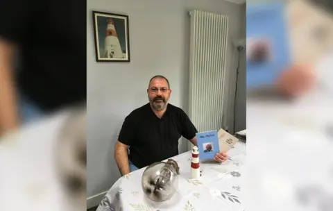 Adrian Underwood Adrian Underwood with his father's books and a model lighthouse he has at his home in Ireland