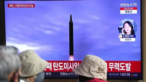 News broadcast with file footage of a North Korean missile test at a railway station in Seoul