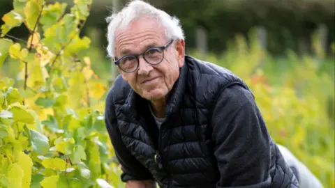 Wendy Wilmot A man stood in a vineyard smiling into the camera