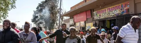 AFP South African looters run off an alleged foreign-owned shop