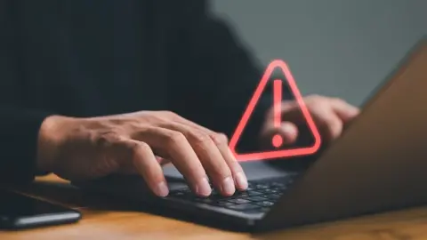 Getty Images Data breach hand over warning sign laptop