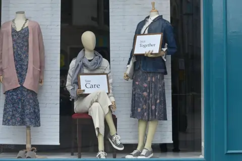 Pacemaker Mannequins in a Belfast clothing shop holding cards that read "take care" and "stick together"