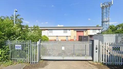 The exterior of an industrial unit behind a large metal gate.