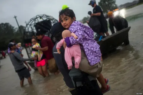 Reuters A girl is rescued from flood waters
