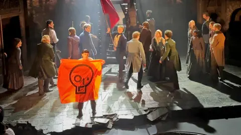 A Just Stop Oil protester holds up an orange banner after disrupting a performance of Les Miserables