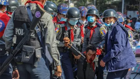 Reuters Police carry their injured colleague as people protest against the military coup and demand the release of elected leader Aung San Suu Kyi, in Mandalay, Myanmar, February 9, 2021.