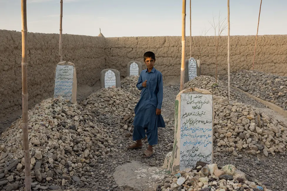 BBC Imran stands by his parents' graves. "I wish our mother and father were with us today," he said. Image: Julian Busch/BBC