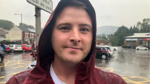 Man in heavy rain in car park of Llynfi Road, Maesteg