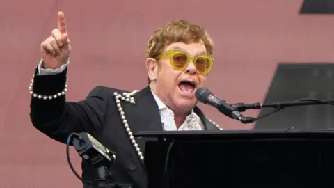 Joe Giddens/PA Elton John singing and playing the piano at Norwich gig