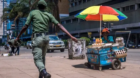 AFP A Zimbabwean soldier walks by a street vendor in Harare's Central Business District main streets on 20 November 2017