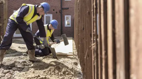 Getty/Monty Rakusen Apprentice builders laying paving stones on building site - stock photo