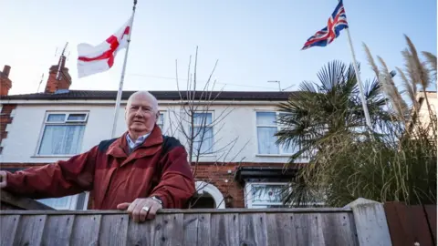 BBC Ian Durrant with the Union Flag and the cross of St George in front of his house in Lincoln