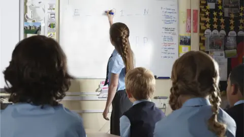 Getty Images Children writing on a whiteboard at school