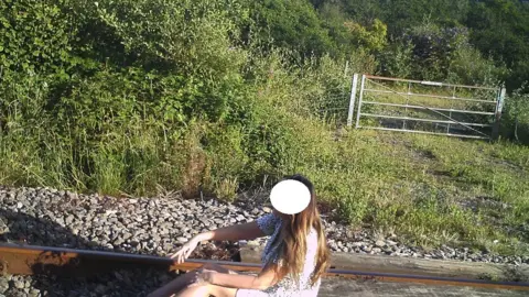 Network Rail A woman sits on the track