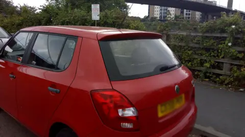 A parked car with a sign behind it