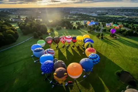 Ben Birchall/PA Wire An aerial view of hot air balloons arranged in a heart shape on the ground in Bristol