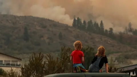 Reuters Local children watch firefighting efforts amid heavy smoke from the Eagle Bluff wildfire