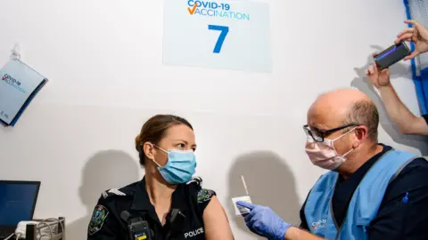 EPA A police officer receives the Pfizer vaccine at a clinic in Adelaide