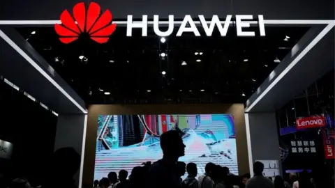 Reuters People walk past Huawei stall