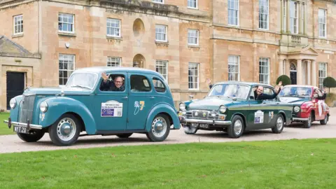 Sean Spencer/Hull News & Pictures Ltd Three drivers wave from the window of a blue, green and red car, as they are  about to leave a manor house.