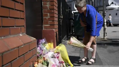 Getty Images Woman lays flowers in Finsbury Park