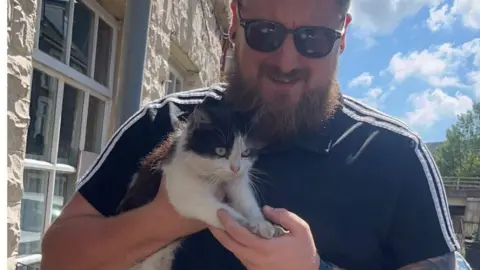 Tom Hutchings  Taxi driver Tom with the cat he found trapped inside his car's grille