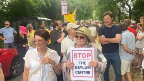 Mousumi Bakshi/BBC Protesters in Wethersfield, Essex holding banners