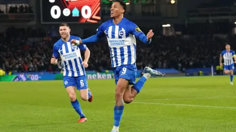 PA Media João Pedro celebrating his goal v Marseille with James Milner chasing him