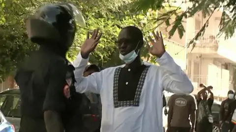 Protester with arms raised faces a police officer