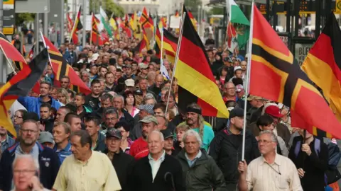 Getty Images Supporters of the Pegida movement march through Dresden with German flags on 27 July, 2015.